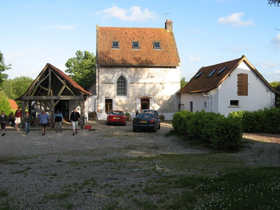The gravel courtyard in front of the house, with the covered terrace, the chapel and the west wing, cars parked