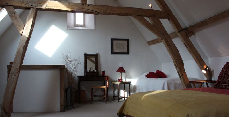 The attic bedroom under the roof, with exposed oak beams and a skylight