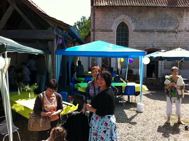 Guests under blue gazebos in the courtyard beside the chapel during a party