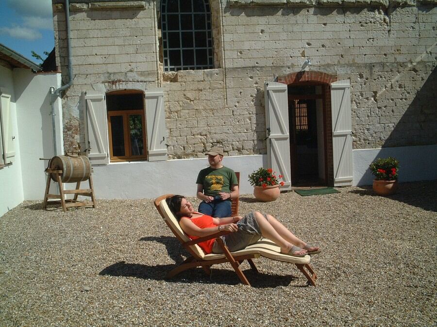 A guest relaxing on a lounger in the sunny courtyard beside the chapel door and shutters