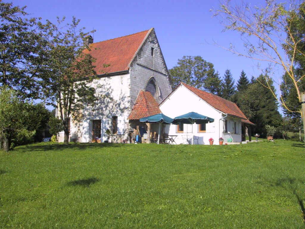 The house from the field, with blue parasols set out on the lawn in front of it