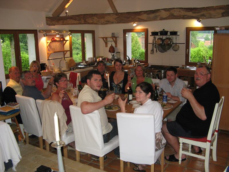 A big group round the long kitchen table, glasses raised, under the old beams