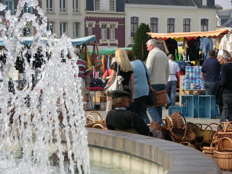 Market stalls in a town square behind a fountain