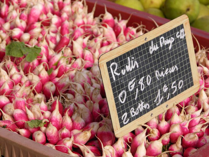 A crate of pink radishes with a handwritten chalk price sign