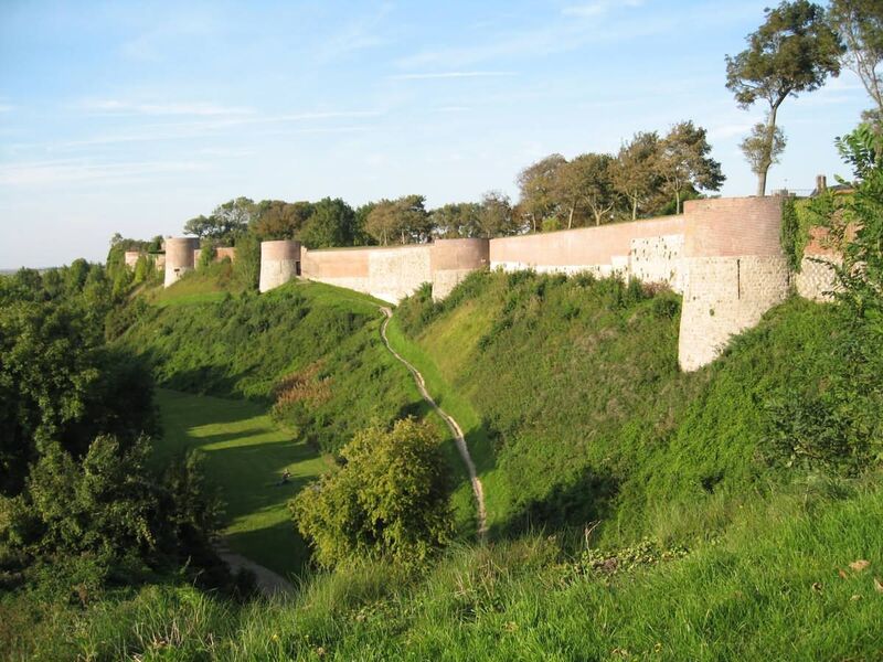 The old stone ramparts of Montreuil above a grassy, wooded slope