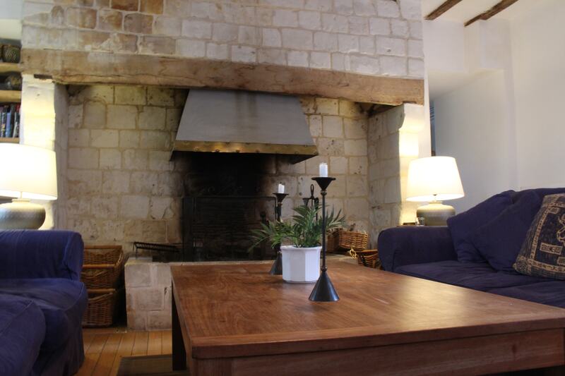 The sitting room: a wide stone fireplace, blue sofas and a long wooden coffee table with candlesticks