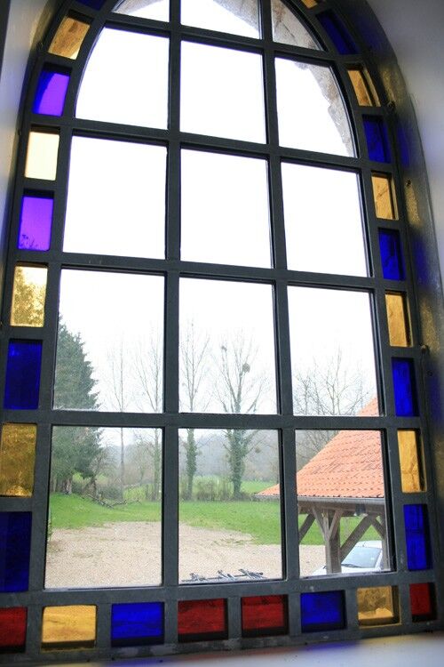 The arched window from inside, its border of blue, red and yellow glass, looking out to the garden