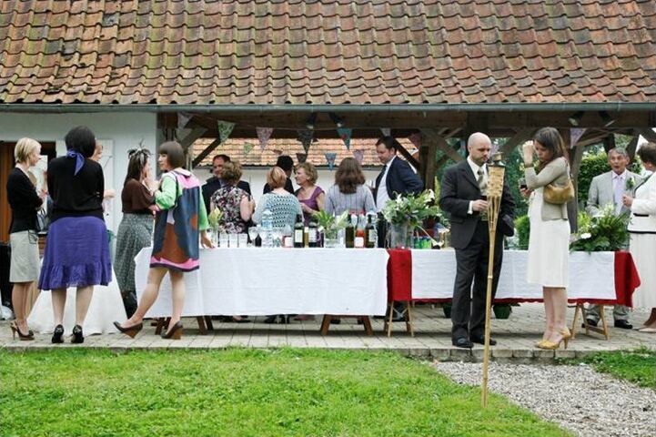 Wedding guests at long tables laid with white cloths under the covered terrace